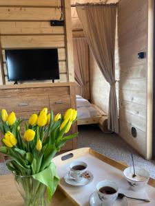 a room with a table with a vase of yellow flowers at Rajski Domek in Sadowie