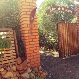 uma parede de tijolos com uma placa e um portão de madeira em Sítio Estrela da Manhã em Palmeiras