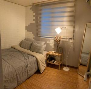 a bedroom with a bed and a lamp and a window at Yakorea Hostel Dongdaemun in Seoul