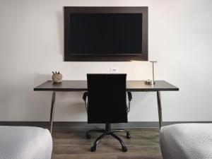 a desk with a chair and a television on a wall at stayAPT Suites Huntsville in Huntsville