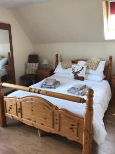 a bedroom with a wooden bed with white sheets at Druid View B&B in Inverness +8 photos