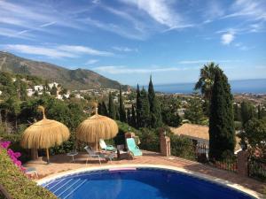 einen Pool mit Sonnenschirmen und Meerblick in der Unterkunft Casa Castana, Mijas Pueblo in Mijas