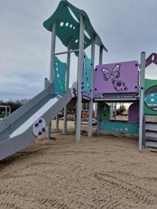 a playground with a slide in the sand at Domki i pokoje Angelo z sauną i jacuzzi- Karwia in Karwia