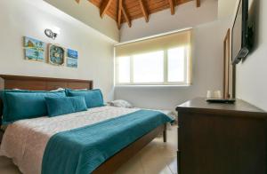 a bedroom with a bed with blue pillows and a window at PENTHOUSE AGUAMARINA in San Andrés