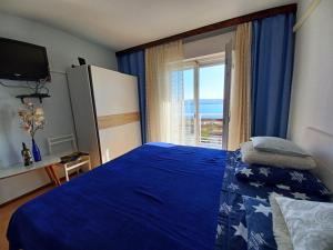 a bedroom with a blue bed with a large window at Guest House Djurdjica in Dramalj