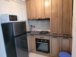 a kitchen with wooden cabinets and a black refrigerator at Alina apartament 2 in Năvodari