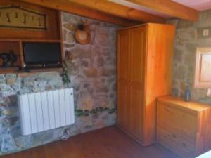 Cette chambre est dotée d'un mur en pierre, d'une télévision et d'une porte. dans l'établissement Casa Rural El Cotu en Cangas de Onís, à Cangas de Onís
