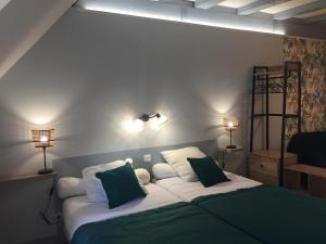 una camera da letto con un grande letto con cuscini verdi e bianchi di Chambres D'hôtes Du Domaine De Jacquelin a Saint-Germain-du-Puy