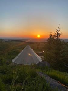 a white tent on top of a hill at sunset at Refuge de la banne in Murat-le-Quaire