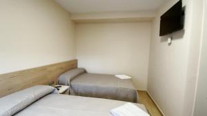 Habitación pequeña con 2 camas y TV de pantalla plana. en Hostal Restaurante Cuatro Caminos, en Cubillos del Sil