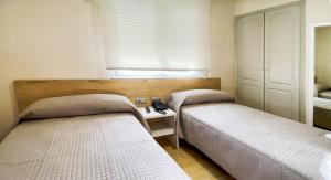 a bedroom with two beds and a desk and a window at Hostal Restaurante Cuatro Caminos in Cubillos del Sil