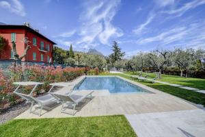 a swimming pool with chairs and a house at Maison Bellini 4 in Toscolano Maderno