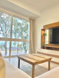uma sala de estar com uma mesa de centro e uma grande janela em Espectacular departamento sobre la laguna para parejas em Chascomús