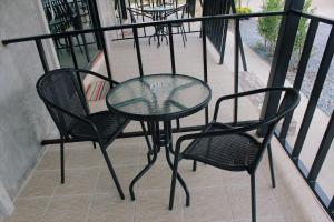 a glass table and two chairs on a balcony at บ้านทองสุข รีสอร์ท in Ban Dao Ruang