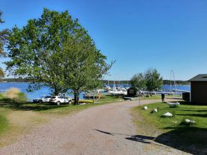 a gravel road next to a tree and a lake at Havsnära Nybyggd Modern villa uthyres året runt! in Mönsterås