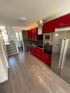 una cocina con armarios rojos y electrodomésticos de acero inoxidable en Apartment Soleil Altamar en Playa de las Américas
