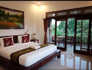 a bedroom with a large bed and a large window at Putra Bisma Guesthouse in Ubud