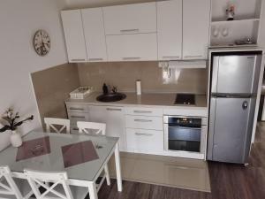 a kitchen with white cabinets and a table and a refrigerator at Apartman Aleksic in Jagodina