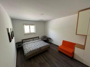 a bedroom with a bed and a orange chair at Guest House Černe in Vrhnika