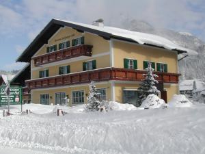a building in the snow in front of a mountain at Pension Salzburger Hof in Fuschl am See