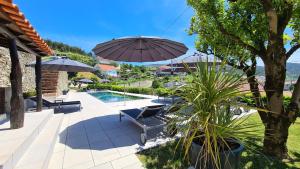 een patio met stoelen, een parasol en een zwembad bij Quinta da Palmeira - Country House Retreat & Spa in Cerdeira
