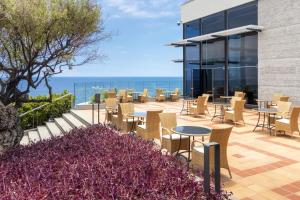 a patio with tables and chairs and the ocean at Royal Savoy - Ocean Resort - Savoy Signature in Funchal