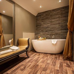 a bathroom with a soaking tub and a bench at The Castle Hotel, Conwy, North Wales - The Coaching Inn Group in Conwy