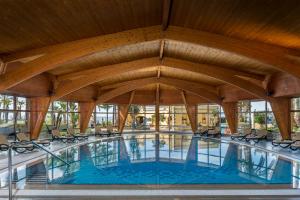 a large swimming pool with chairs and a wooden ceiling at Royal Savoy - Ocean Resort - Savoy Signature in Funchal