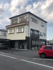un bâtiment avec une voiture rouge garée devant lui dans l'établissement 今市STAY - NIKKO private house rental only 5 min to station, à Nikkō