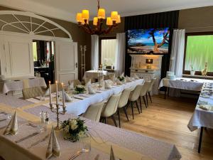 um quarto com uma longa mesa com mesas e cadeiras brancas em Freigeist • Pension & Brasserie em Witzin