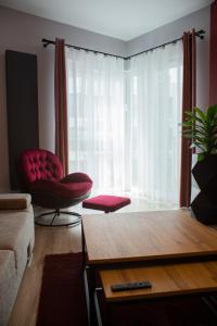 een woonkamer met een rode stoel en een groot raam bij APARTAMENT ELEGANCE RED w Let's Sea in Gąski
