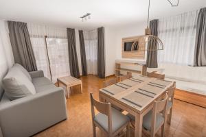 a living room with a dining room table and a couch at Apartments Niko in Santa Eularia des Riu