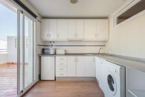 cocina con armarios blancos, lavadora y secadora en Apartamento Tarifa Sol, en Tarifa