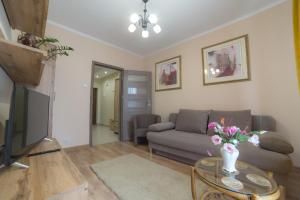 Una sala de estar con un sofá y una mesa con flores. en Noclegi na Ogrodowej, en Sandomierz