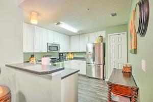 a kitchen with white cabinets and a stainless steel refrigerator at Cheery Condo with Community Pool and Waterslide! in Pine Bluff