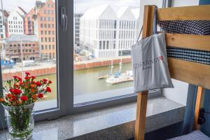 a window with a view of a river and a vase of flowers at Hostel Gdańsk Szafarnia 10 Old Town in Gdańsk