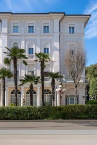 un edificio bianco con palme di fronte di Residenza Parco Fellini a Rimini