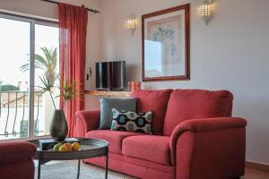 a red couch in a living room with a table at 2BR Duplex Townhouse with access to Pool - 5mn to Beach by LovelyStay in Ferragudo