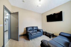 een woonkamer met een bank en een televisie bij Magee Town House 'Sleeping 11 guests' in Londonderry County Borough