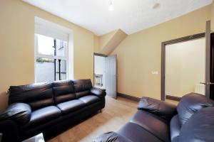 a living room with a leather couch and a window at Magee Town House 'Sleeping 8 guests' in Londonderry County Borough