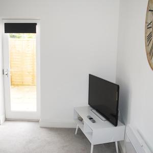 ein Wohnzimmer mit einem Flachbild-TV auf einem weißen Tisch in der Unterkunft Bellevue Apartment in Bristol