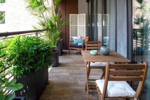 un patio con mesa de madera, sillas y plantas en Madeleine apartments - Appartamento di charme en Milán