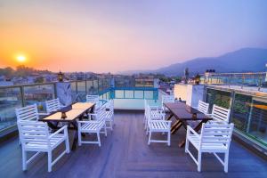 a balcony with tables and chairs on a building at Hotel Holy Vivasa in Rishīkesh
