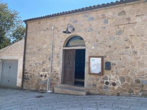 un bâtiment en pierre avec une porte sur son côté dans l'établissement Bed and Bike Antico Mulino, à Aglientu