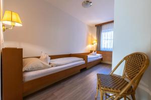 a bedroom with a bed and a chair and a window at Pension Apartments Klotznerhof in Schenna