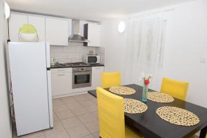 a kitchen with a dining table and yellow chairs at Vera in Silba