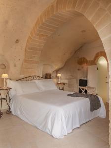 een slaapkamer met een wit bed in een stenen muur bij Palazzo Degli Abati in Matera +214 foto's
