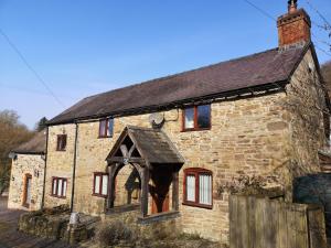 een oud stenen huis met een gewelfde deuropening bij The Old Smithy Bed & Breakfast in Craven Arms