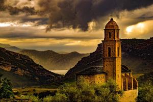 una torre del reloj en una colina con montañas al fondo en casa di Rosa, en Patrimonio