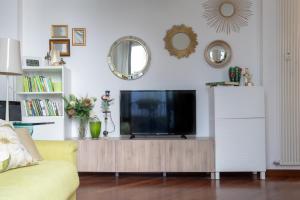 sala de estar con TV en un centro de entretenimiento de madera en Madeleine apartments - Residenza Belle Époque, en Milán